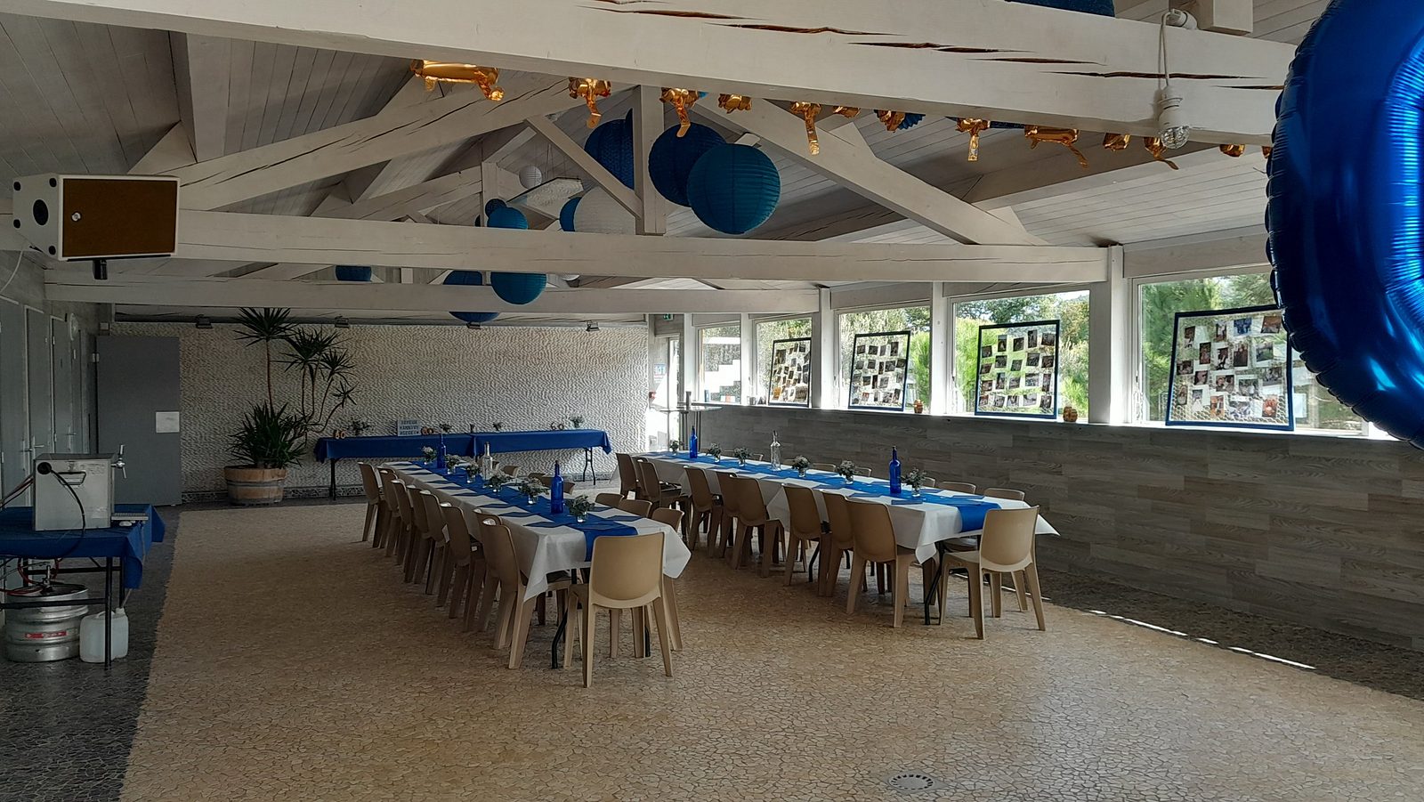La salle décorée de bleu et de blanc pour une fête, longues tables dressées