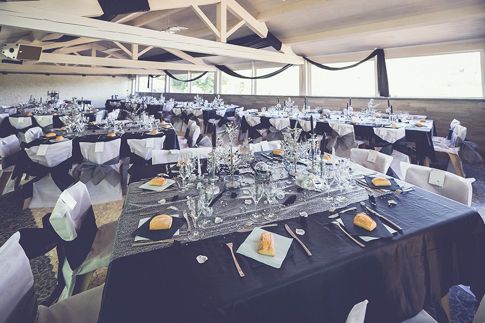 La salle Altesse dressée pour un mariage, nappes sombres et housses de chaises blanches