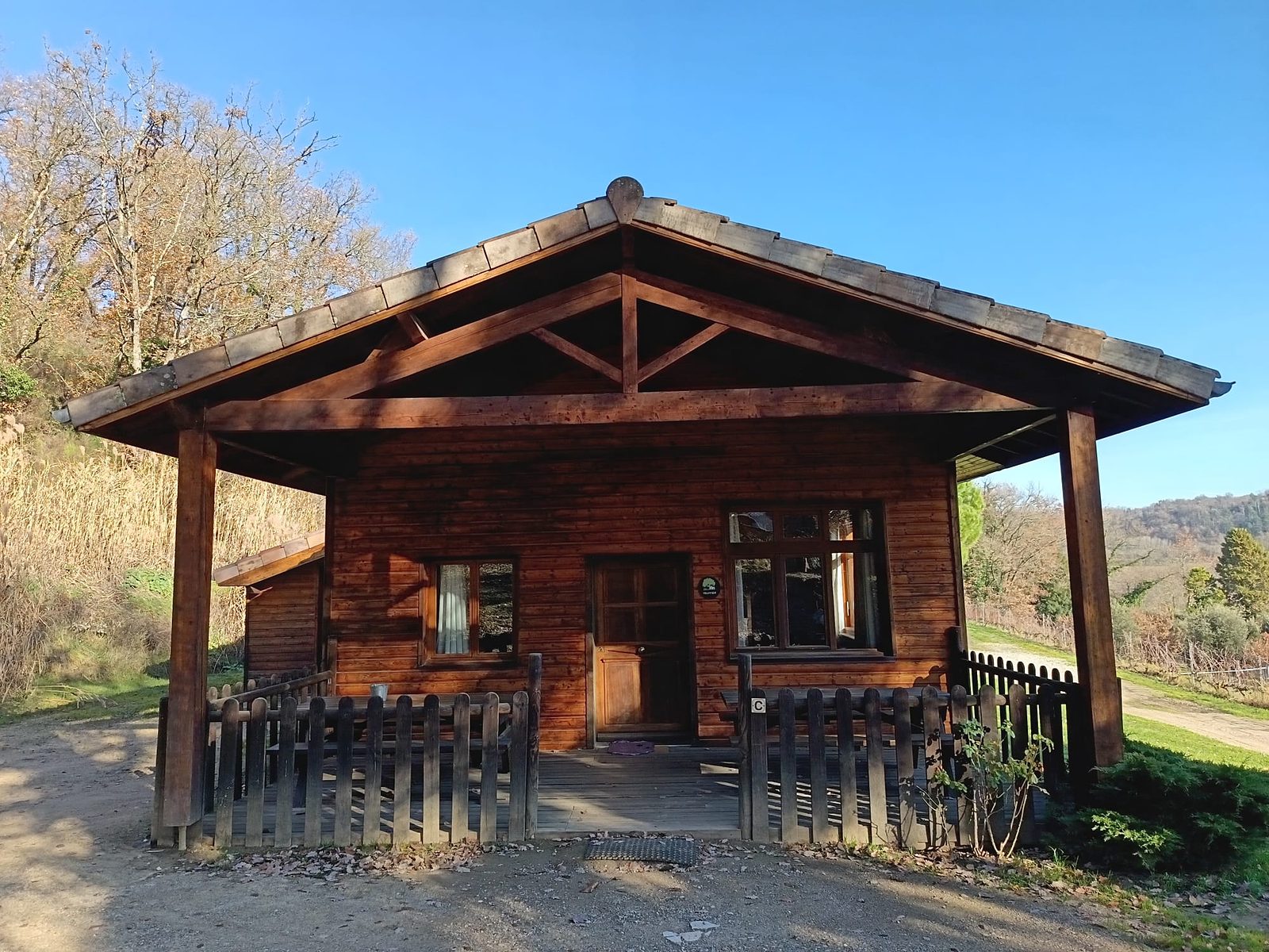 Un chalet en bois du domaine et sa grande terrasse couverte, au soleil