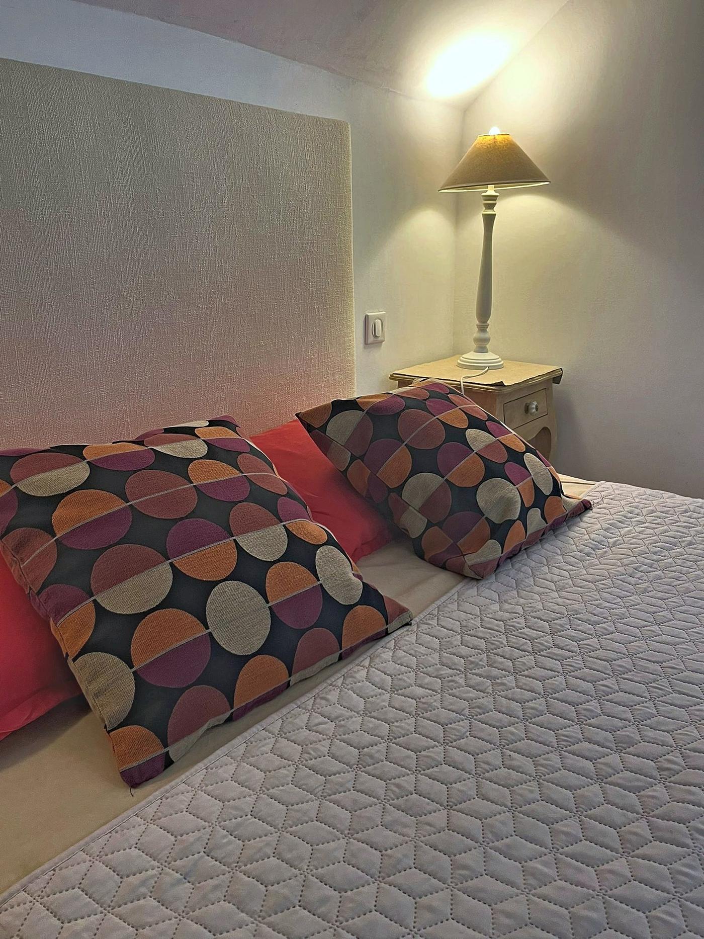 Le lit du Colombier et ses coussins à motifs