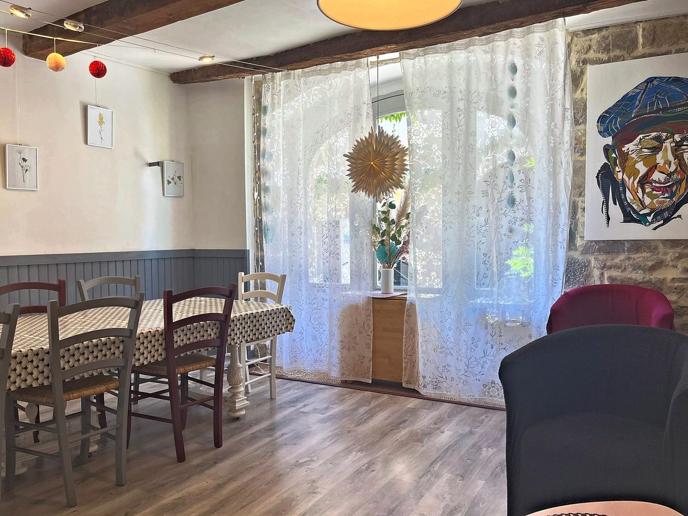 La table dressée devant la fenêtre à rideaux de dentelle