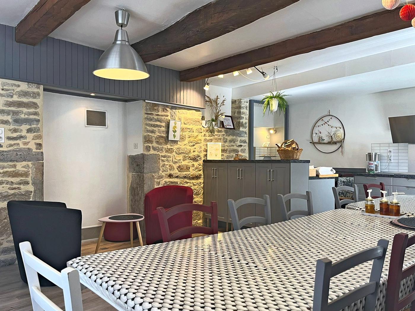 La grande table de la salle à manger, sous les poutres et le mur de pierre