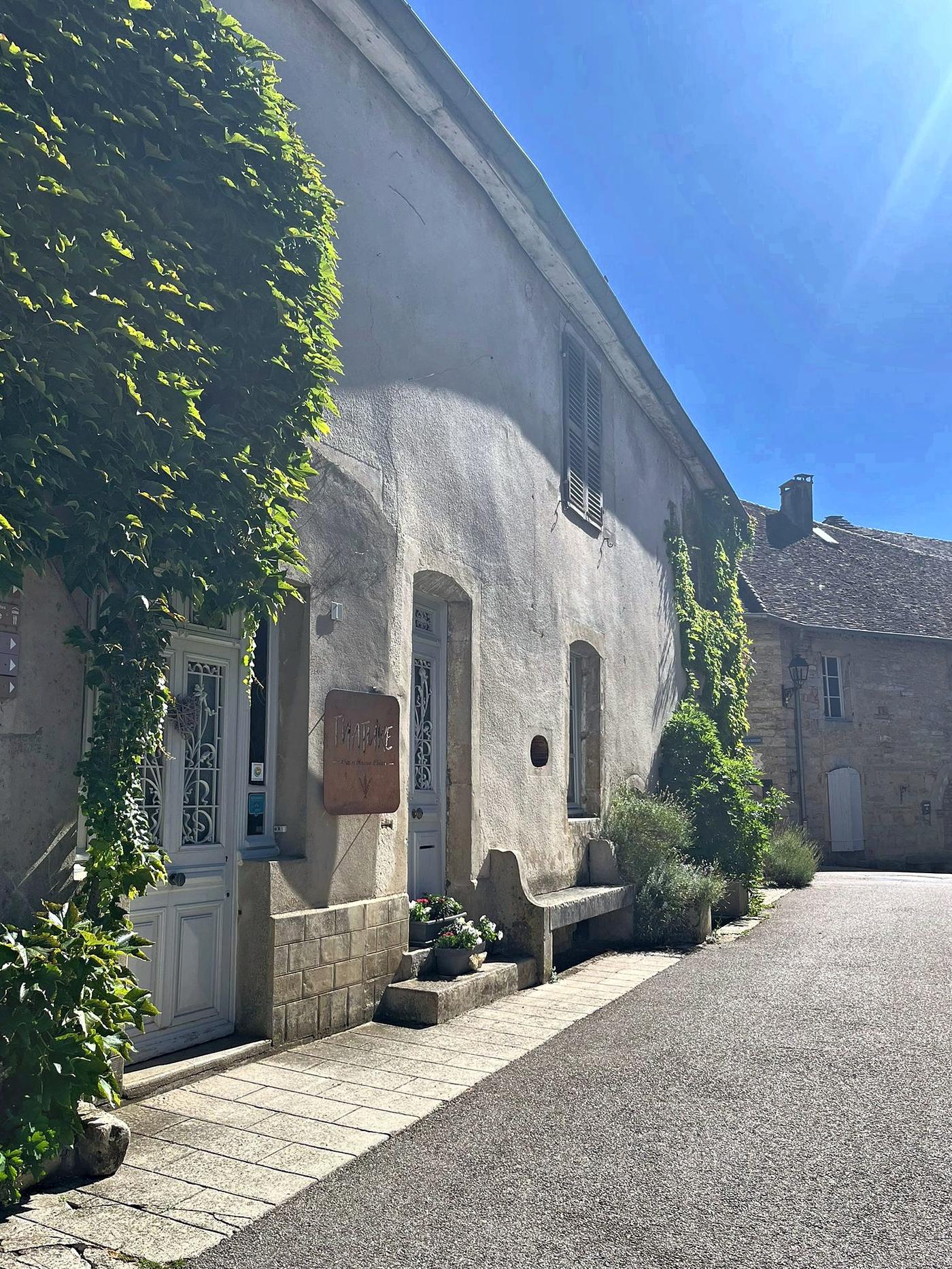 La façade en pierre de la maison, couverte de vigne vierge, dans la ruelle du village