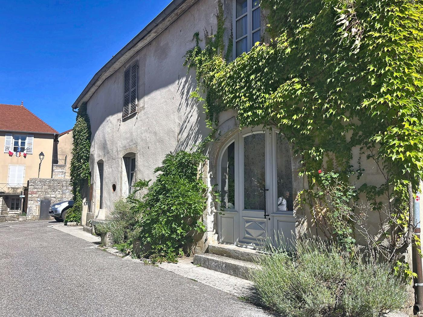 La maison en pierre dans la ruelle du village, sous la vigne vierge