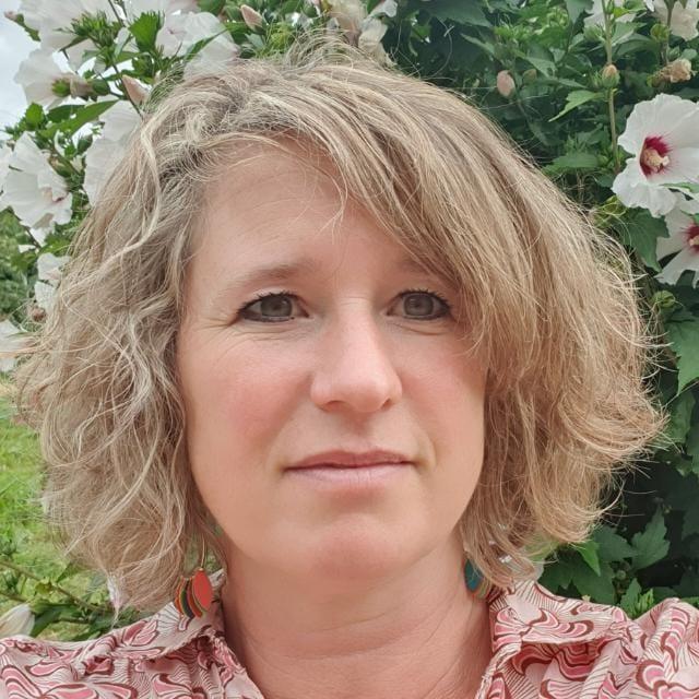 Marie, qui vous accueille à T’Nature, devant un hibiscus en fleurs